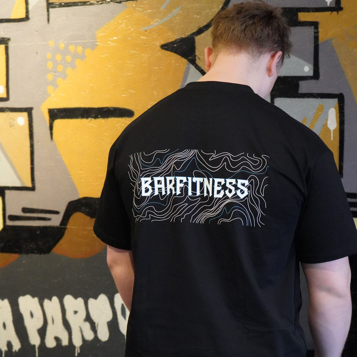 Person iført sort Barfitness T-shirt med grafisk ryglogo.