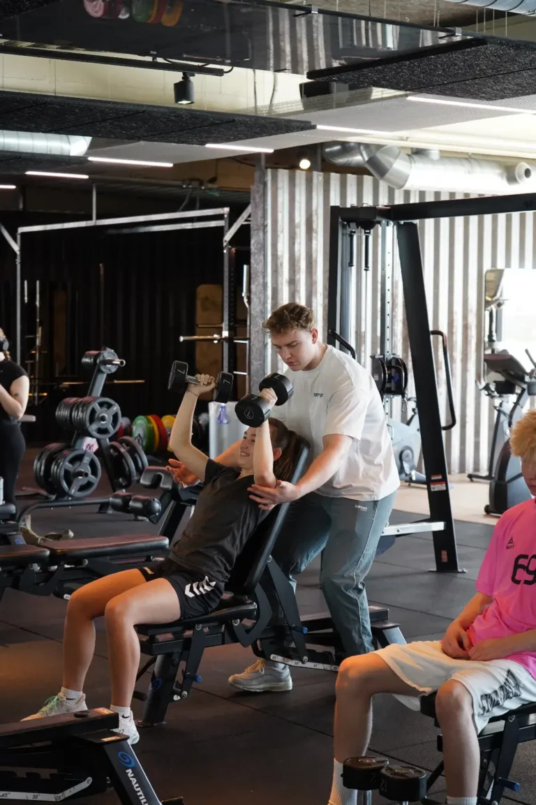 Stephan Sørensen hjælper en klient med styrketræning i fitnesscenter.